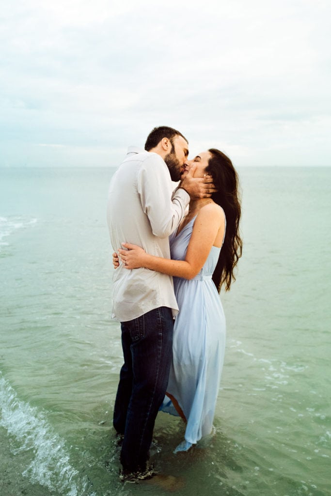 Elopement Photographer, man and woman kiss as they stand in the quiet ocean tide