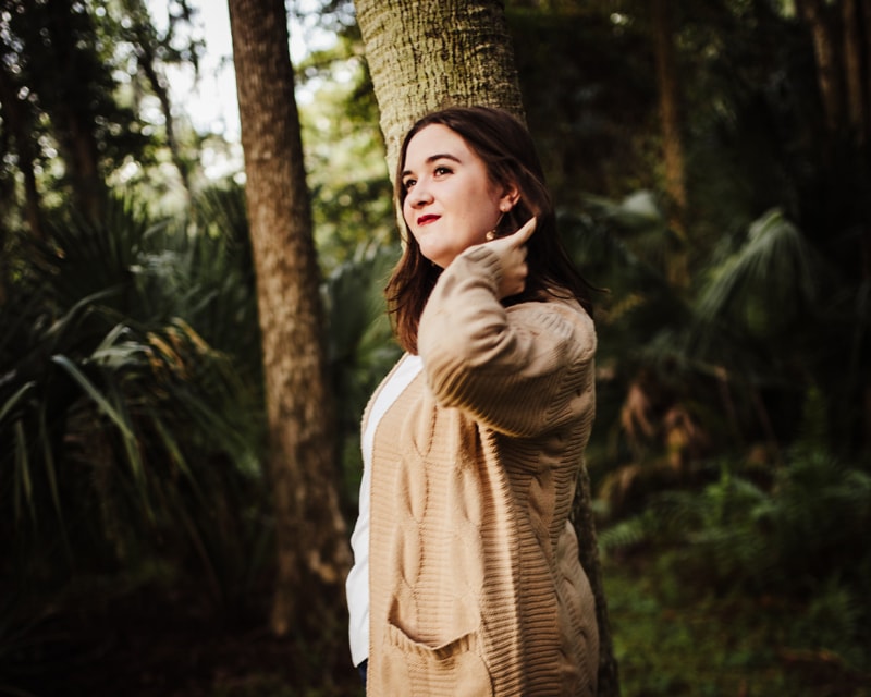 Family Photographer, a woman stands confident and happy beneath forest trees